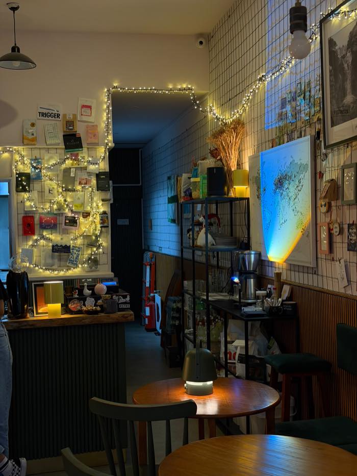 A sala do DOM ao serão, com luzes de fio e mesas redondas de madeira.